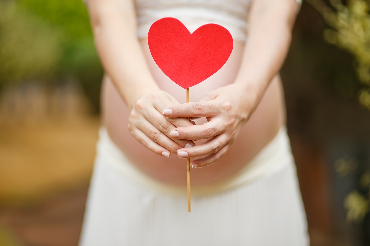 Terhes nő szívvel a kezében